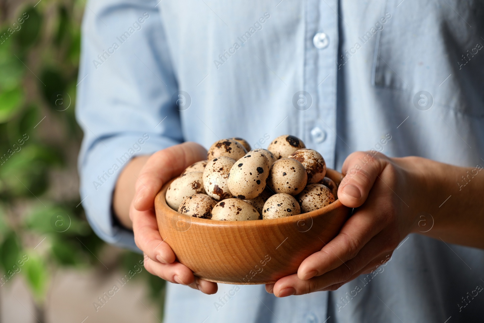 Photo of Woman with bowl of quail eggs indoors, closeup