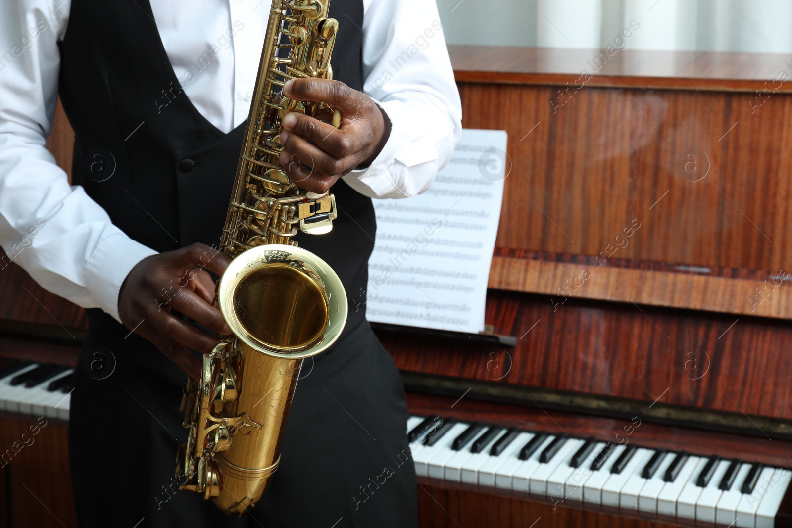 Photo of African-American man playing saxophone indoors, closeup with space for text. Talented musician