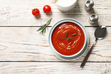Photo of Bowl with fresh homemade tomato soup and space for text on wooden table, top view