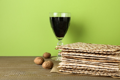 Photo of Passover matzos, glass of wine and walnuts on wooden table. Pesach celebration