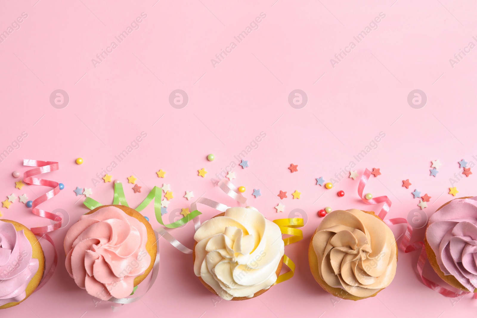 Photo of Flat lay composition with delicious birthday cupcakes and space for text on color background