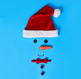 Photo of Creative snowman shape made of Santa hat and different items on light blue background, flat lay