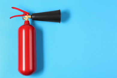 Photo of Fire extinguisher on light blue background, top view. Space for text