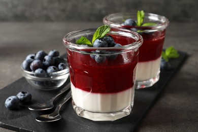 Photo of Delicious panna cotta with fruit coulis and fresh blueberries served on grey table