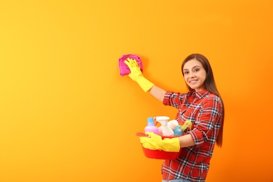 Young woman cleaning color wall with rag