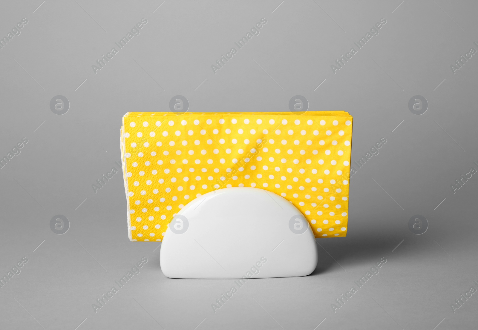 Photo of Ceramic napkin holder with paper serviettes on gray background