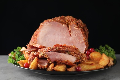 Photo of Plate with delicious ham and potatoes on grey table against black background