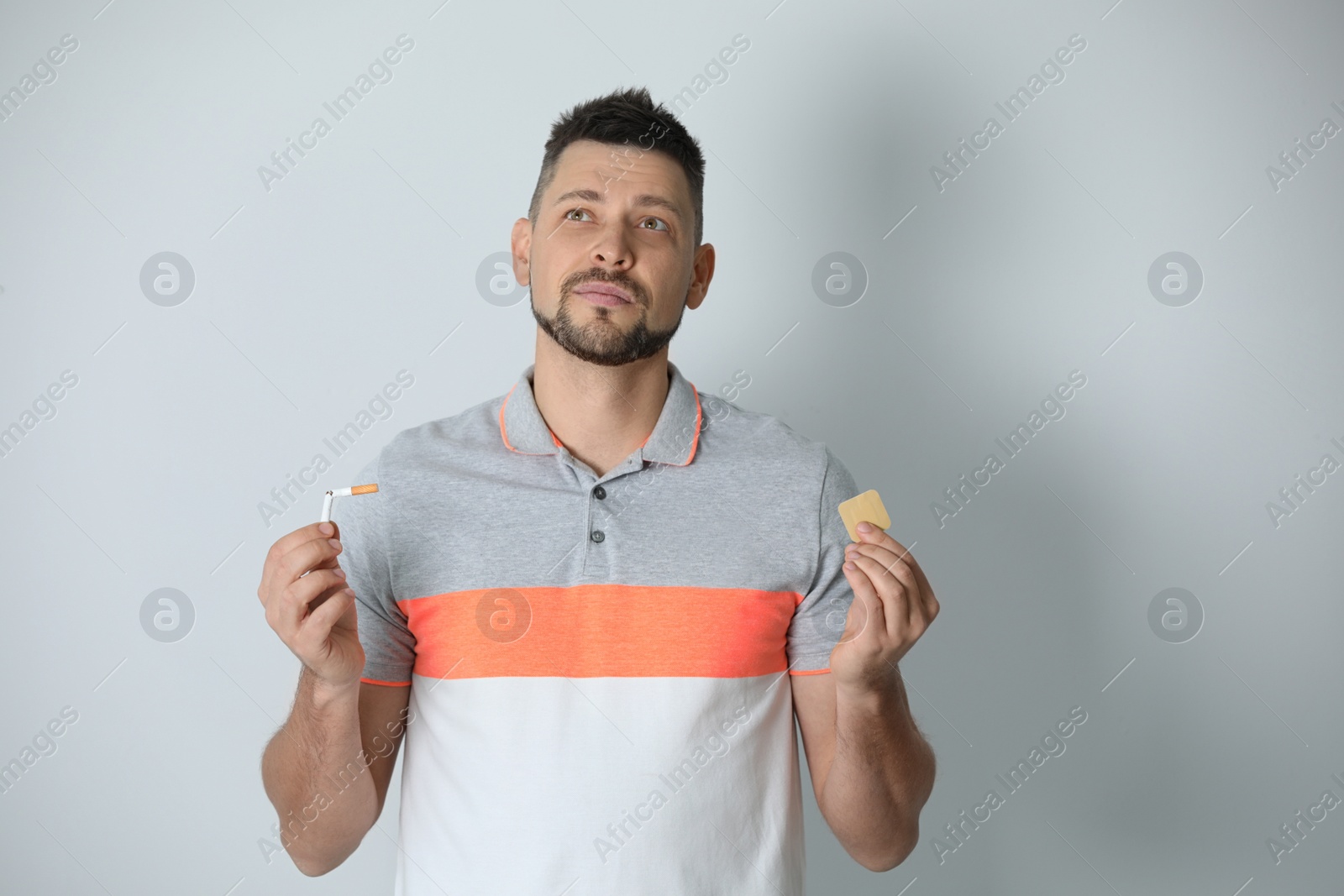 Photo of Thoughtful man with nicotine patch and cigarette on light grey background