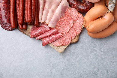 Photo of Different types of sausages on light grey table, flat lay. Space for text