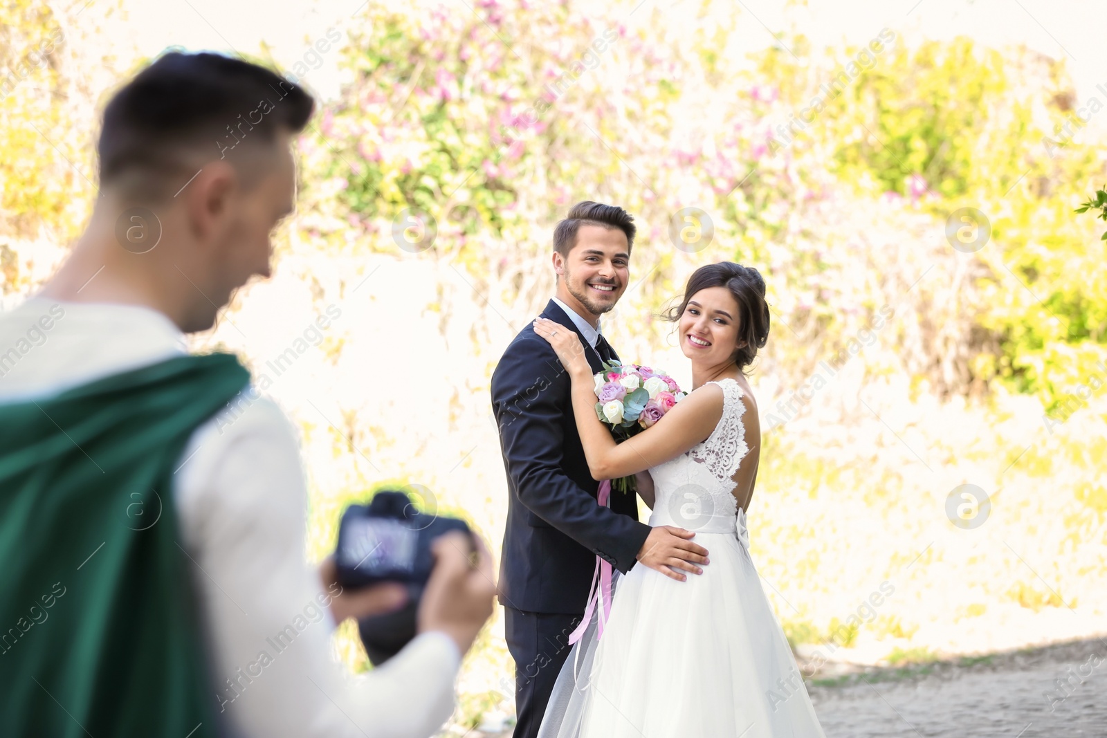 Photo of Wedding couple and professional photographer with camera, outdoors