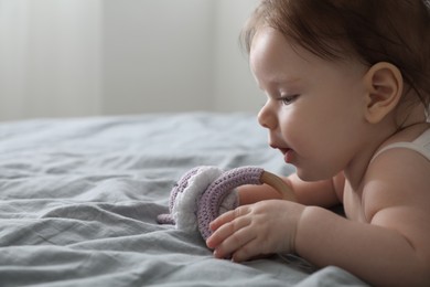 Cute little baby with toy on bed indoors. Space for text