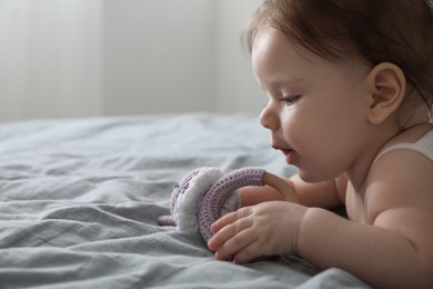 Photo of Cute little baby with toy on bed indoors. Space for text