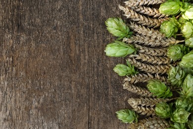 Photo of Fresh green hops and ears of wheat on wooden table, flat lay. Space for text