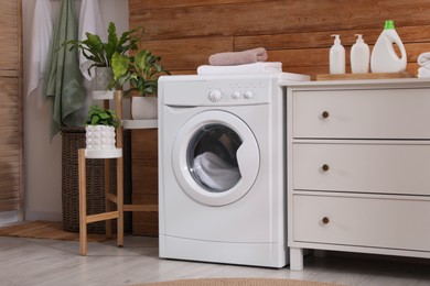 Laundry room interior with washing machine and stylish furniture