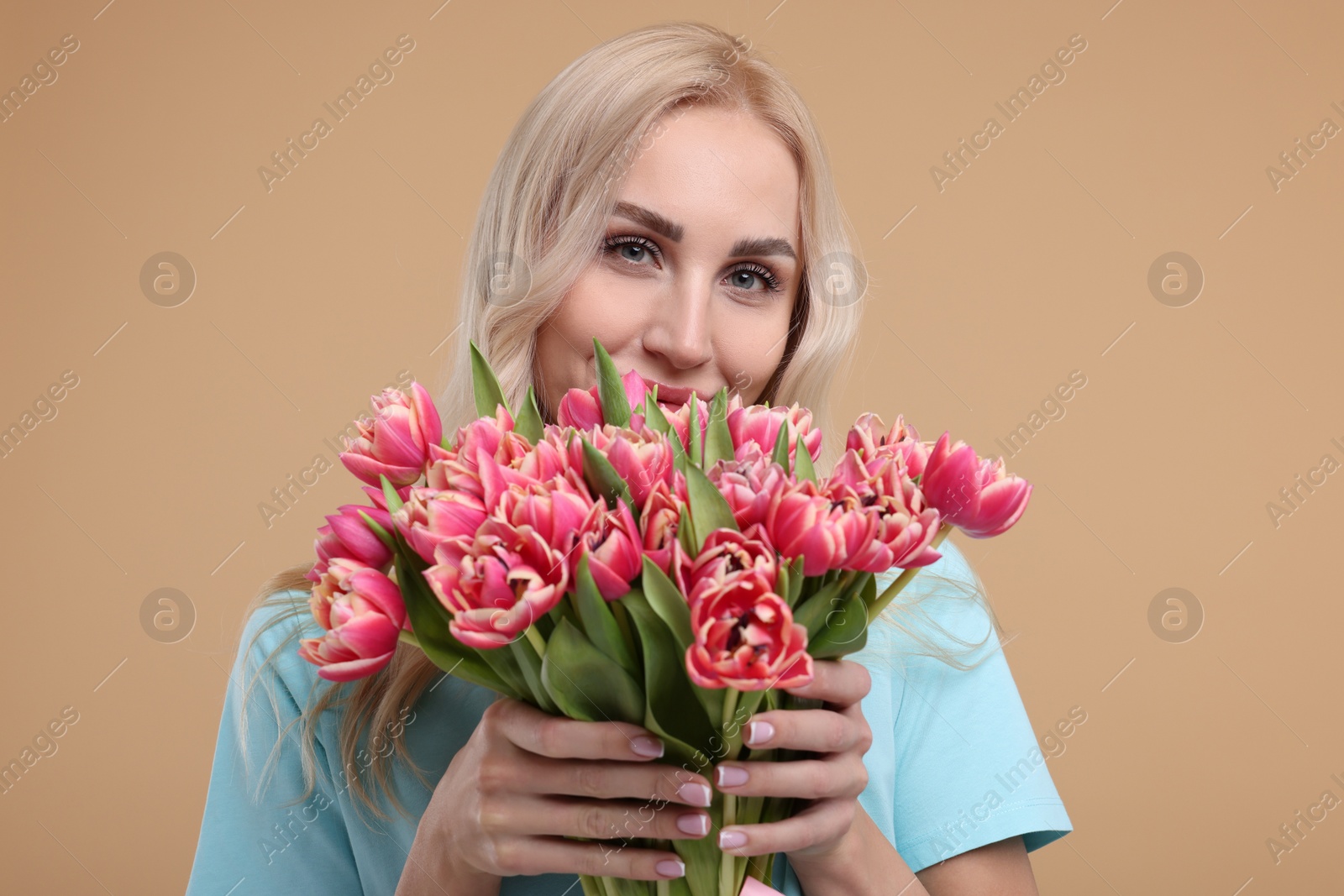 Photo of Happy young woman with beautiful bouquet on beige background