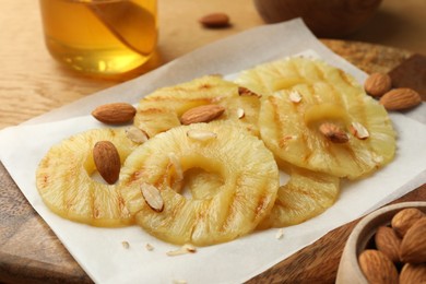Photo of Tasty grilled pineapple slices and almonds on table, closeup