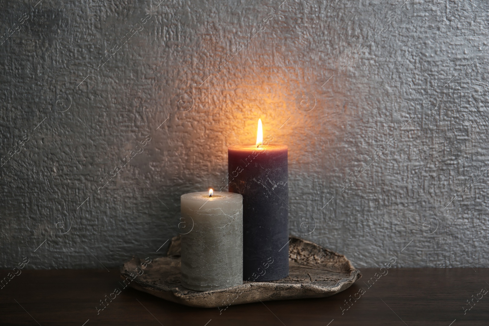 Photo of Decorative candles on table against color background