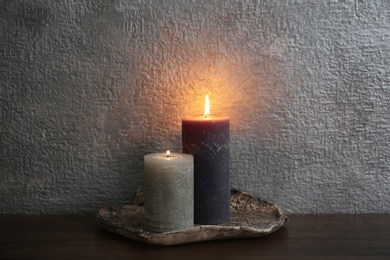 Photo of Decorative candles on table against color background