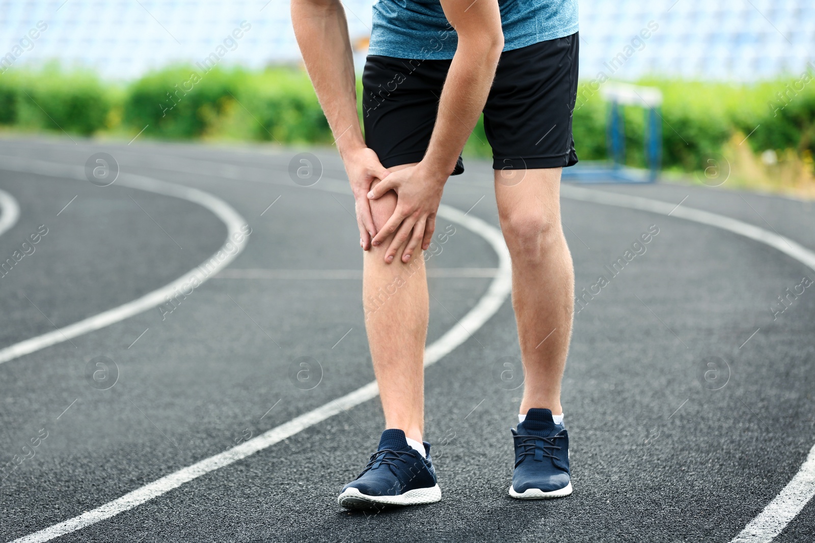 Photo of Man in sportswear suffering from knee pain at stadium, closeup