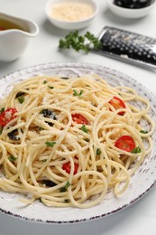 Photo of Delicious pasta with olives, tomatoes and parmesan cheese on white table, closeup