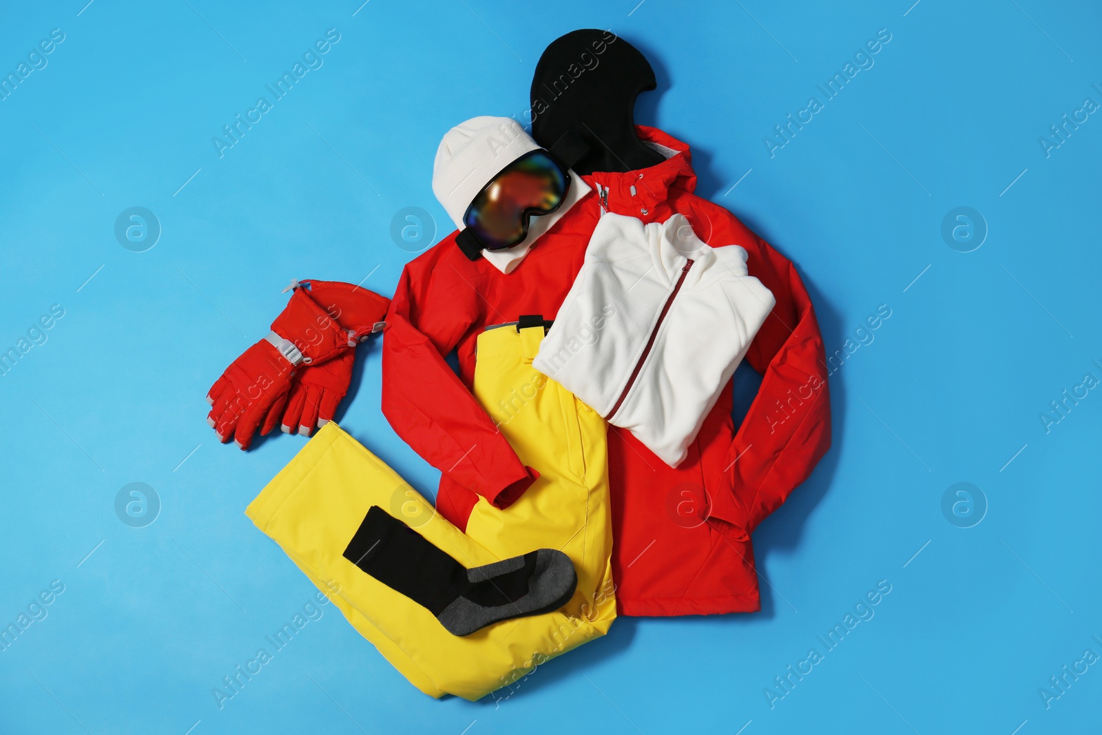 Photo of Stylish winter sport clothes on light blue background, flat lay