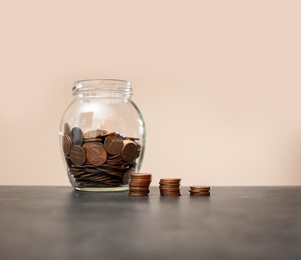 Photo of Donation jar and coins on table against color background. Space for text