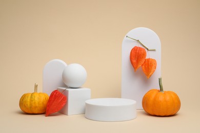 Photo of Autumn presentation for product. White geometric figures, pumpkins and physalises on beige background