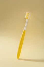 Photo of One plastic toothbrush on pale yellow background