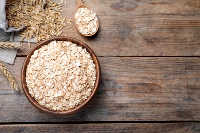 Photo of Bowl with oatmeal on wooden table, flat lay. Space for text