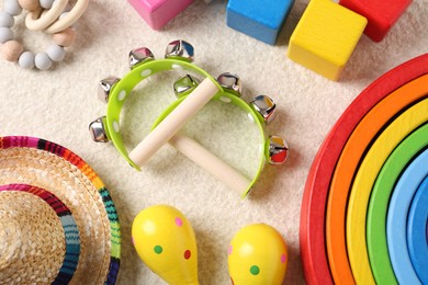 Baby song concept. Wooden tambourines and toys on beige carpet, flat lay