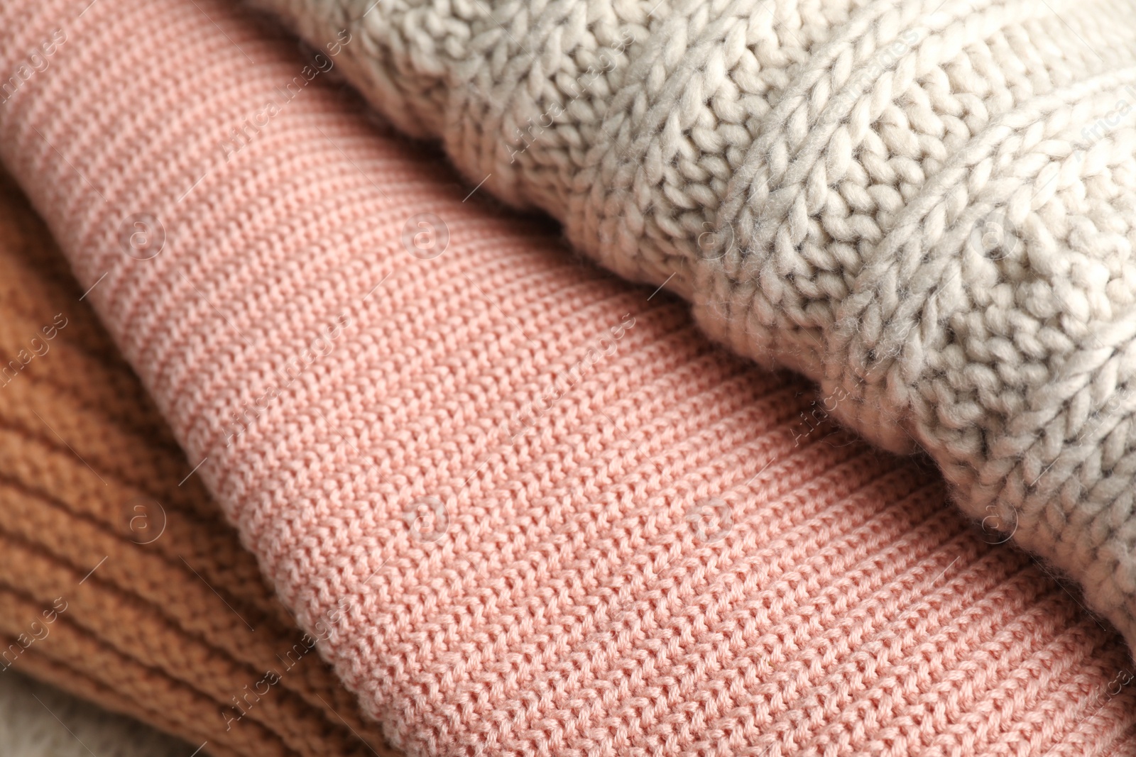 Photo of Stack of folded warm knitted sweaters, closeup