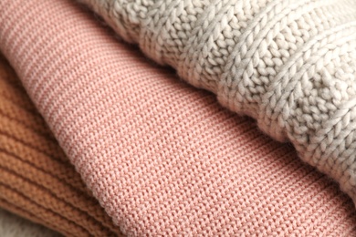 Photo of Stack of folded warm knitted sweaters, closeup