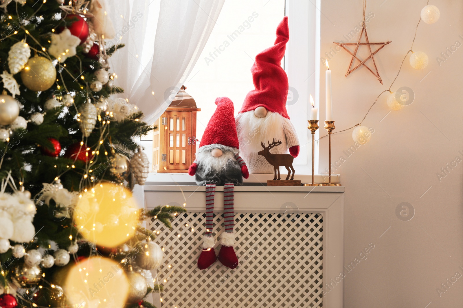 Photo of Cute gnomes near Christmas tree on windowsill in room