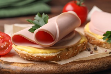 Delicious sandwich with boiled sausage and cheese on board, closeup