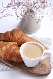 Tasty breakfast. Cup of coffee and croissants on white wooden table