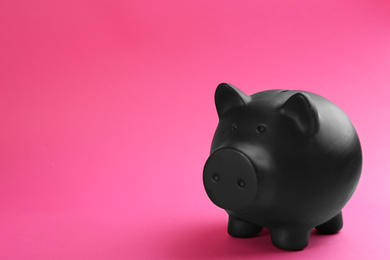 Photo of Black piggy bank on pink background. Space for text