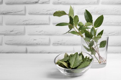 Fresh green bay leaves on white wooden table, space for text