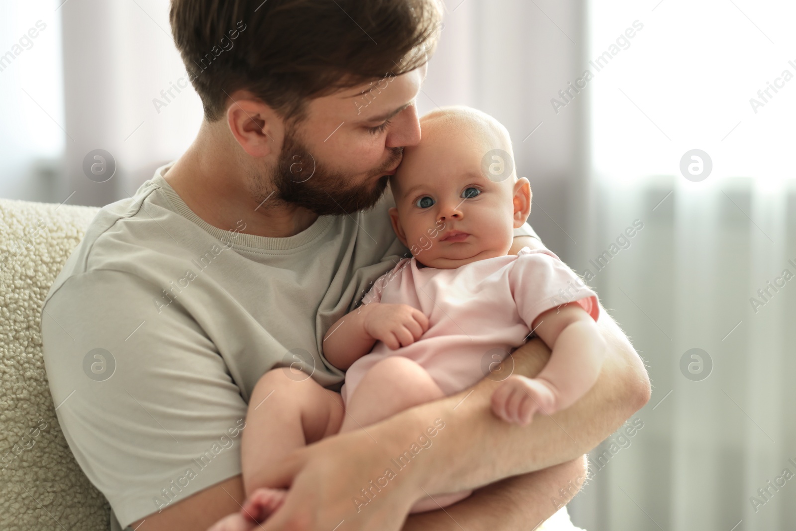 Photo of Father kissing his cute baby in armchair at home