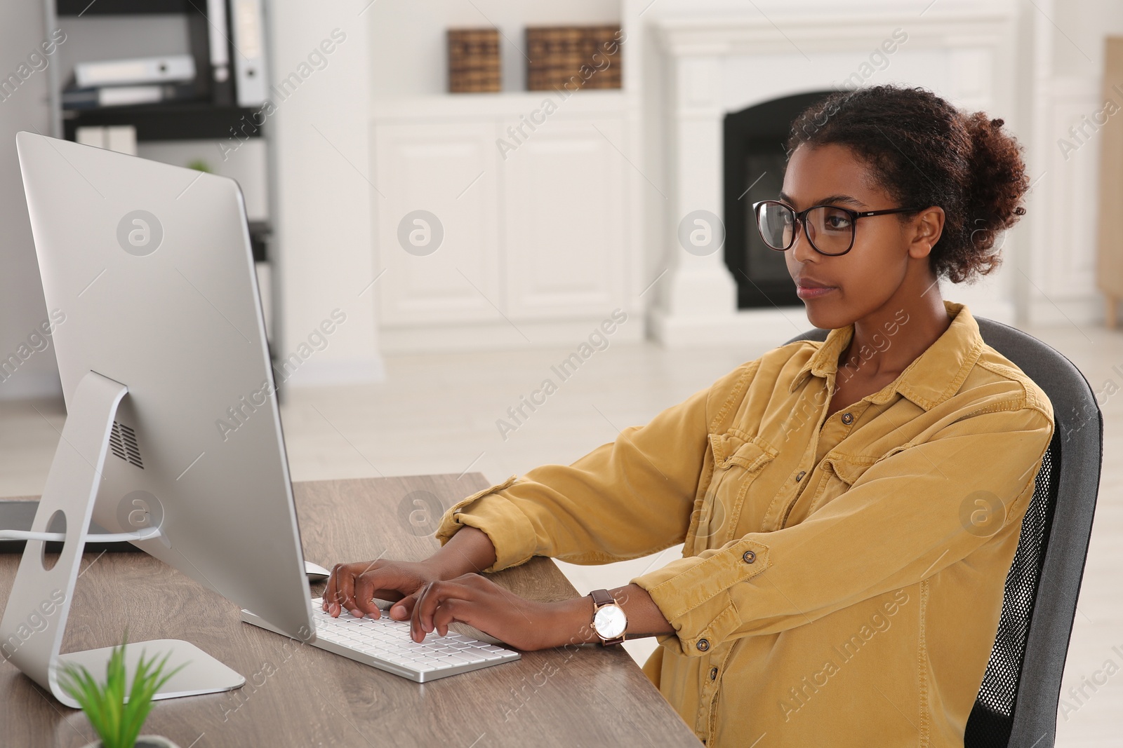 Photo of African American intern working with computer at table in office