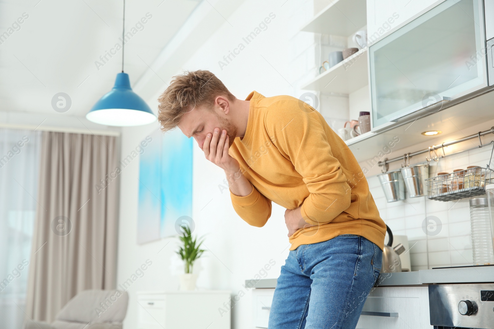 Photo of Young man having nausea in kitchen. Space for text