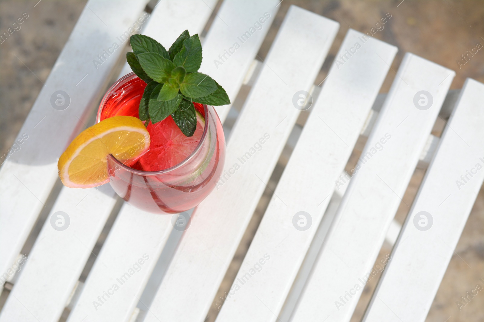 Photo of Glass of delicious cocktail on white wooden table, space for text. Refreshing drink