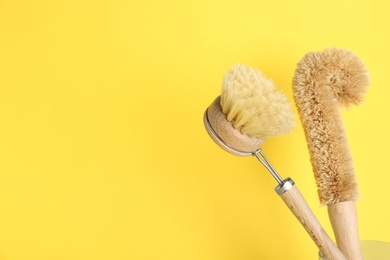 Cleaning brushes on yellow background, space for text. Dish washing supplies