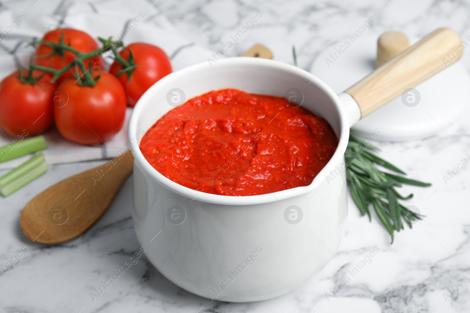 Photo of Delicious tomato sauce in pan on marble table