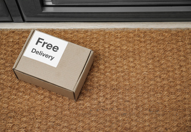 Photo of Parcel with sticker Free Delivery on rug indoors, space for text. Courier service