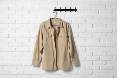 Hanger with beige shirt on white brick wall