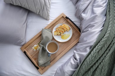 Photo of Aromatic coffee, biscuit and beautiful flower on bed with grey linens indoors, top view