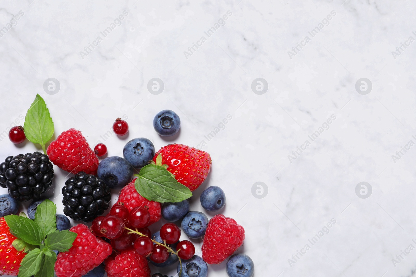 Photo of Many different fresh ripe berries on white marble table, flat lay. Space for text