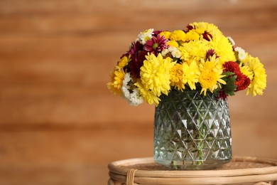 Photo of Bouquet of beautiful chrysanthemum flowers on wicker table indoors, space for text