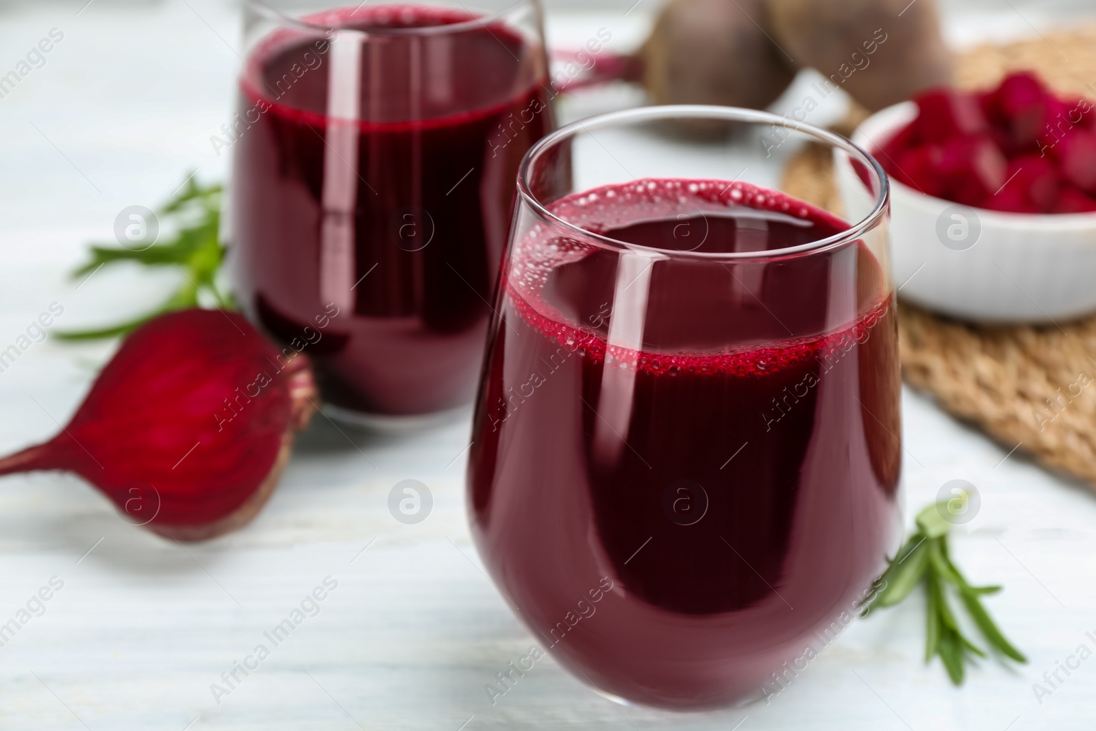 Photo of Fresh beet juice and raw vegetable on white table, closeup