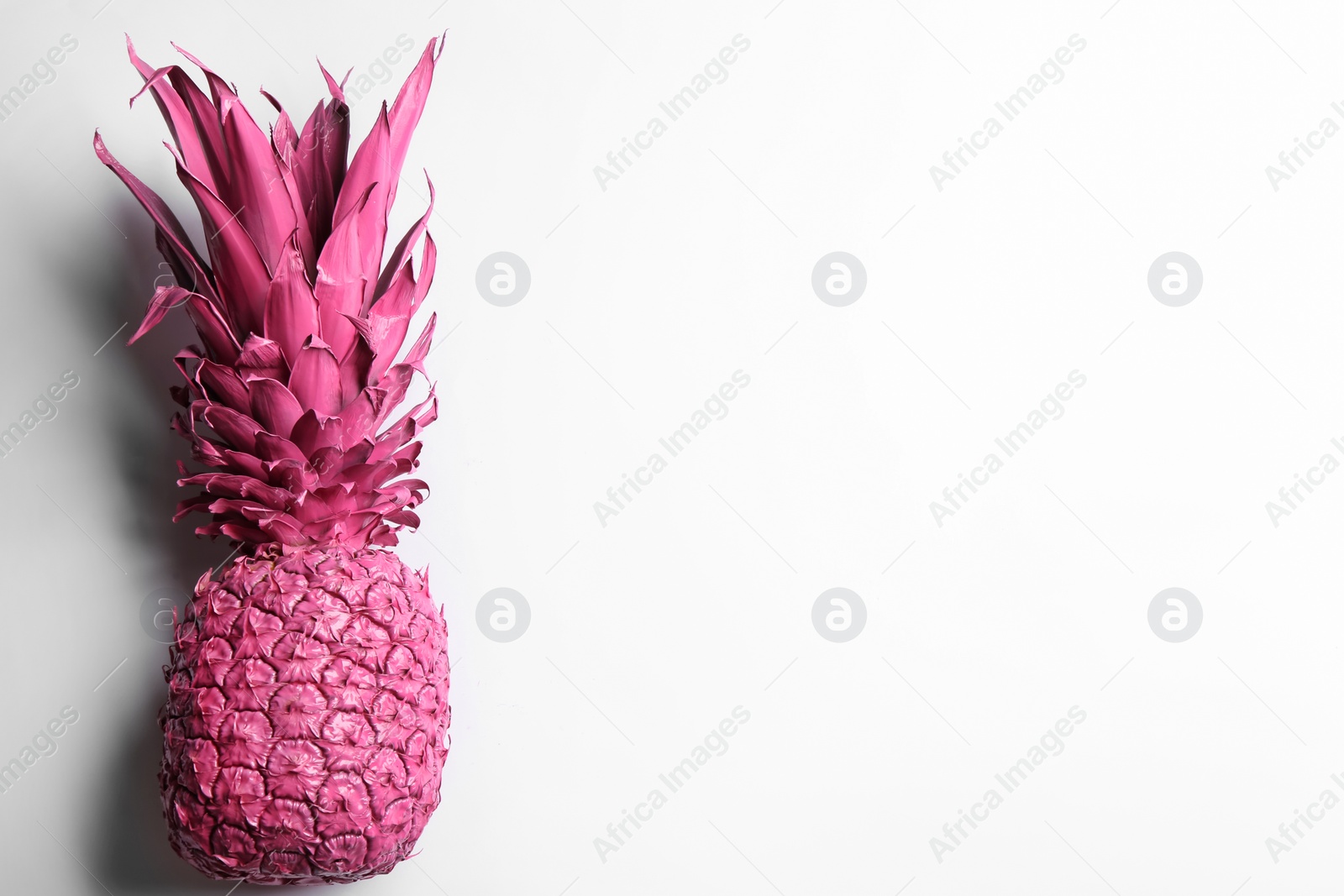 Photo of Painted pink pineapple on white background, top view. Creative concept